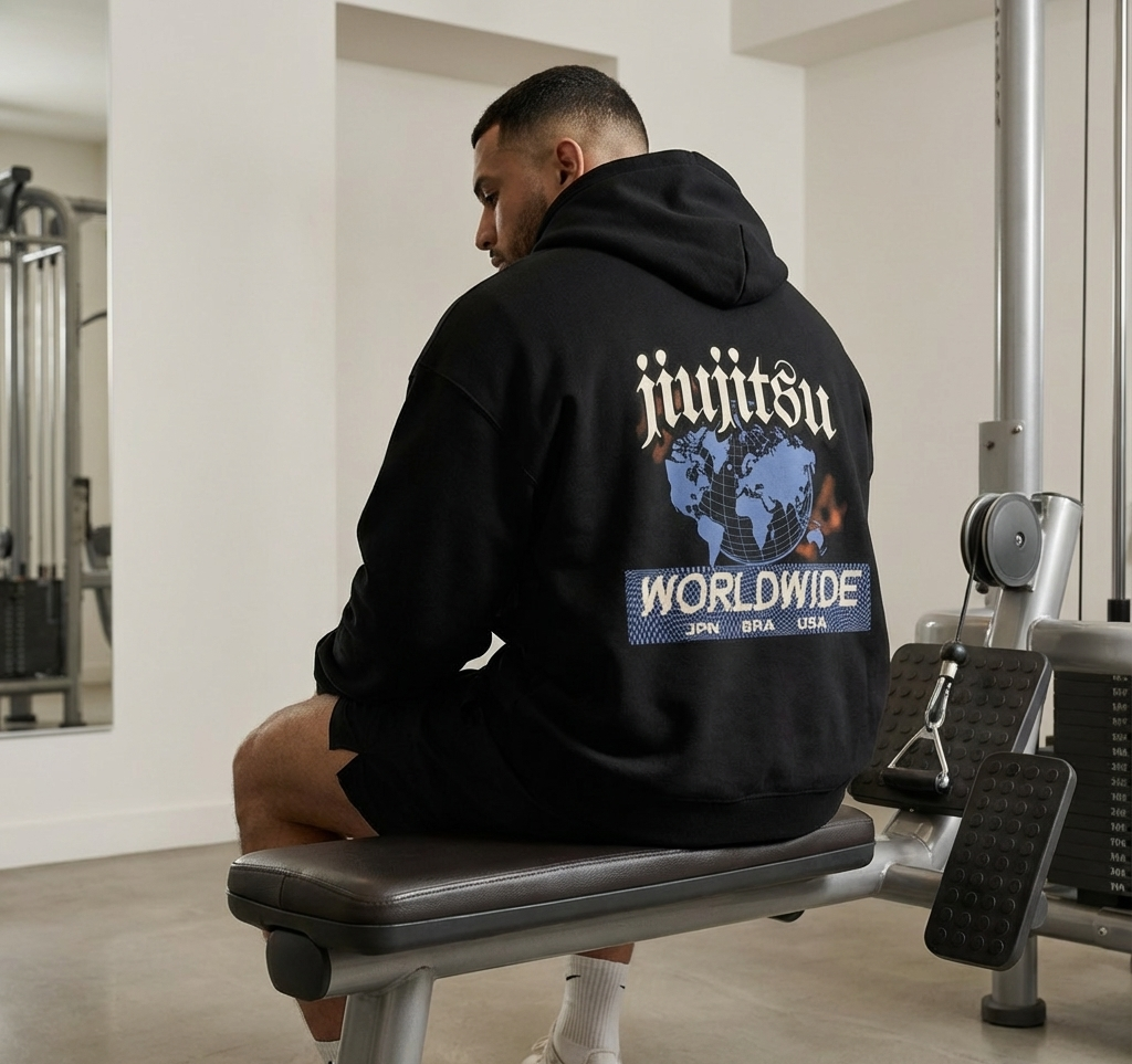 Person wearing a black hoodie with 'jiujitsu worldwide' text in a gym setting